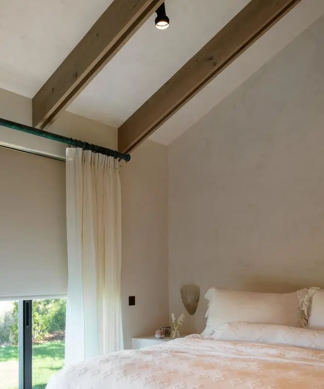Bedroom with a motorized roller shade lowered behind sheer drapery