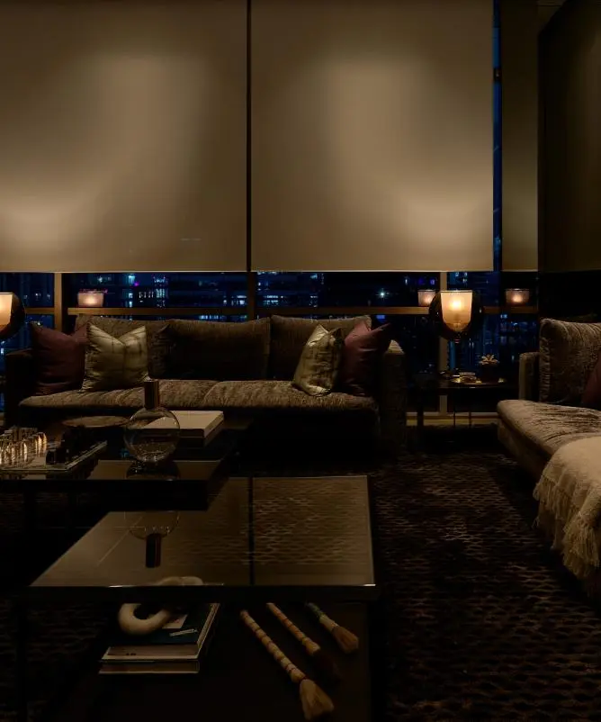 Living room at night with shades lowered and lamps glowing
