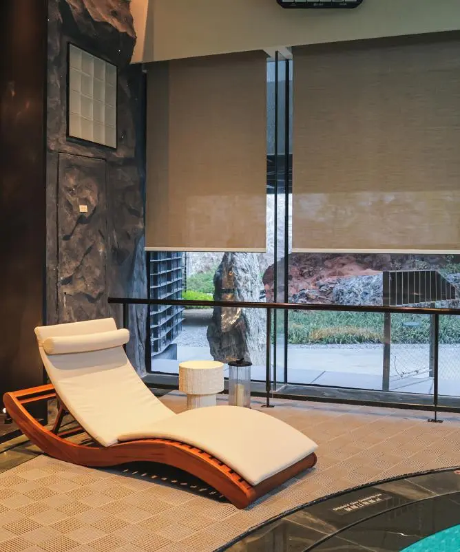 Pool lounge with solar roller shades half lowered over tall windows